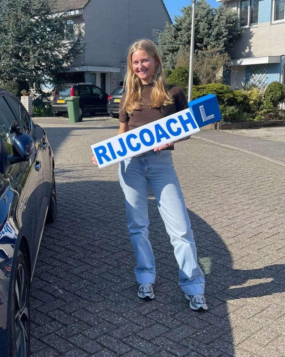 Geslaagde leerling bij Rijcoach Bloemendaal met blauw lesbord