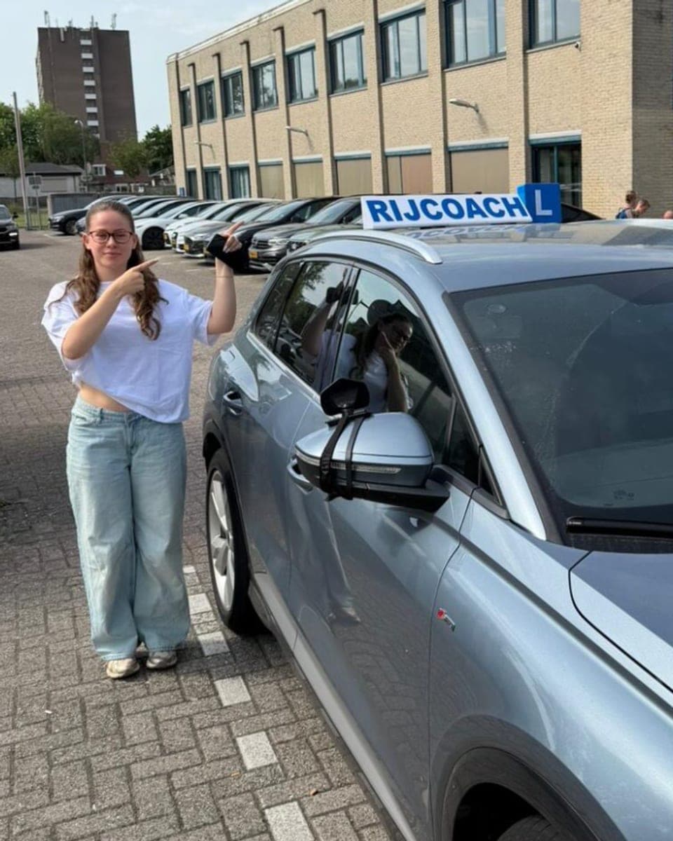 Geslaagde leerling bij Rijcoach Hoofddorp naast de lesauto