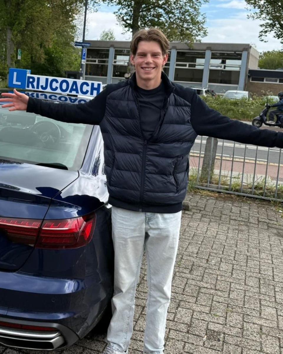 Blije leerling geslaagd bij Rijcoach Hoofddorp naast de lesauto